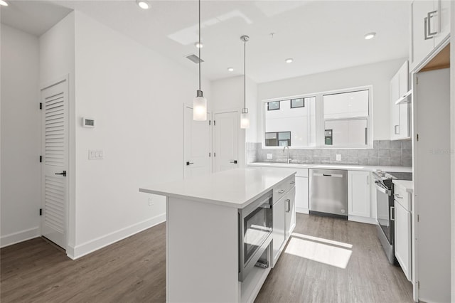 kitchen with white cabinetry, a center island, dark wood-type flooring, stainless steel appliances, and decorative light fixtures