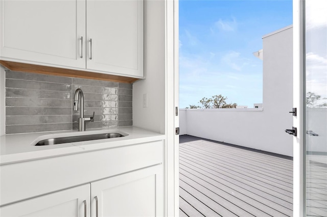 bar with white cabinets, tasteful backsplash, and sink