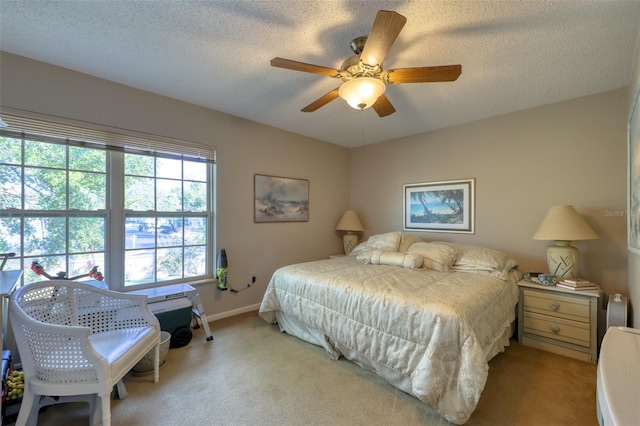 bedroom with ceiling fan, light colored carpet, and a textured ceiling