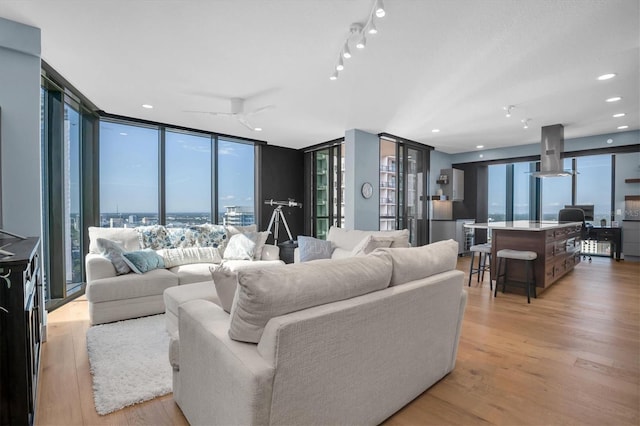 living room featuring a wealth of natural light, light hardwood / wood-style floors, floor to ceiling windows, and ceiling fan