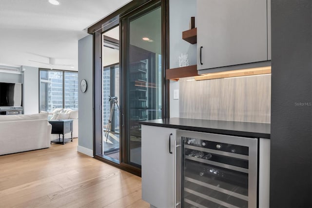 bar featuring floor to ceiling windows, a wall mounted AC, wine cooler, and light hardwood / wood-style flooring