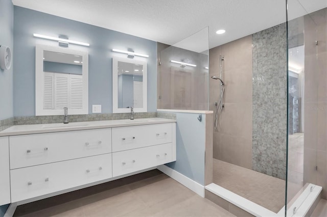 bathroom with vanity, tile patterned flooring, a textured ceiling, and tiled shower