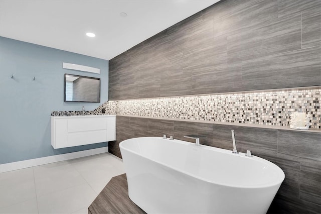 bathroom featuring tile patterned floors, a bathtub, vanity, and tile walls