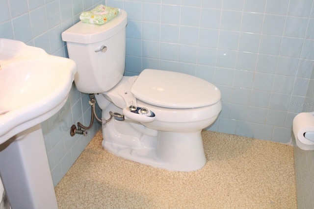 bathroom featuring tile walls and toilet