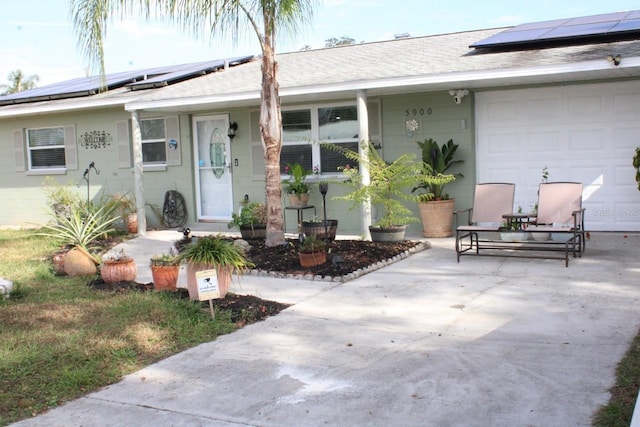 view of front facade featuring a patio, a garage, and solar panels