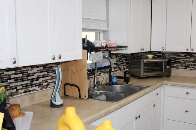 kitchen with white cabinets, sink, and tasteful backsplash