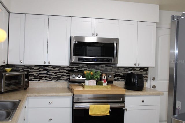 kitchen featuring white cabinets, sink, stainless steel appliances, and tasteful backsplash