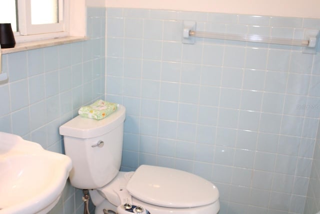 bathroom featuring toilet, tile walls, and sink