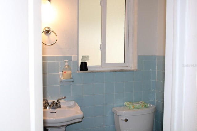 bathroom with sink, tile walls, and toilet