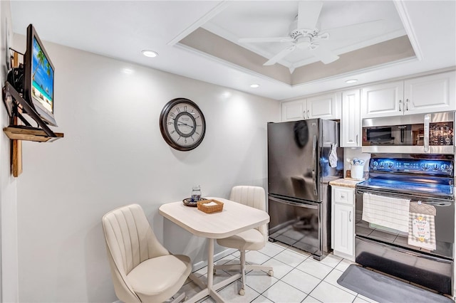 kitchen featuring black refrigerator, range with electric cooktop, a tray ceiling, light tile patterned floors, and white cabinets