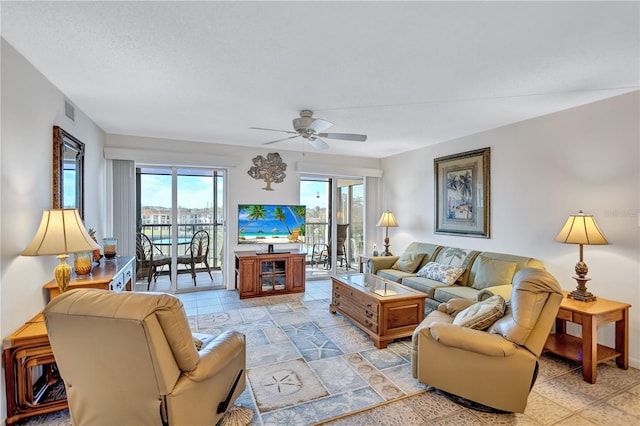 living room featuring ceiling fan and a textured ceiling