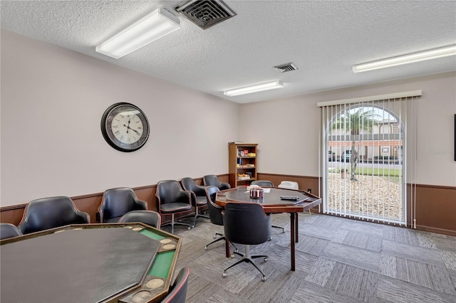 office area featuring a textured ceiling and wooden walls