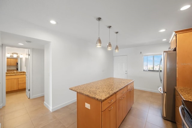 kitchen with light stone countertops, stainless steel fridge, pendant lighting, range, and a center island