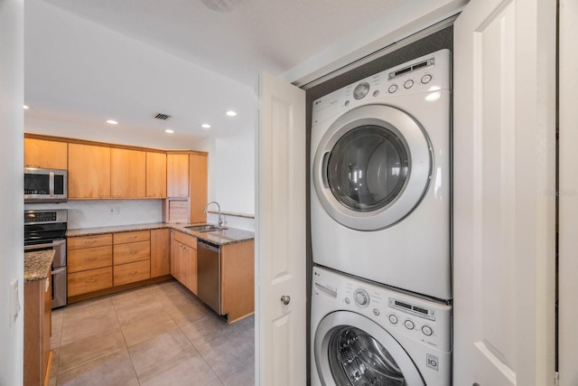 laundry room featuring sink, light tile patterned flooring, and stacked washer / drying machine