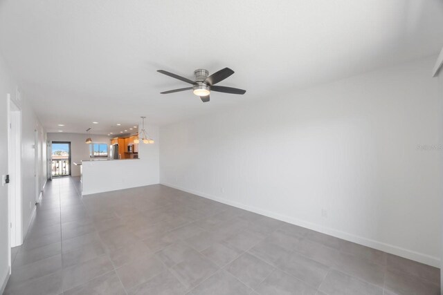 spare room featuring ceiling fan with notable chandelier and light tile patterned floors