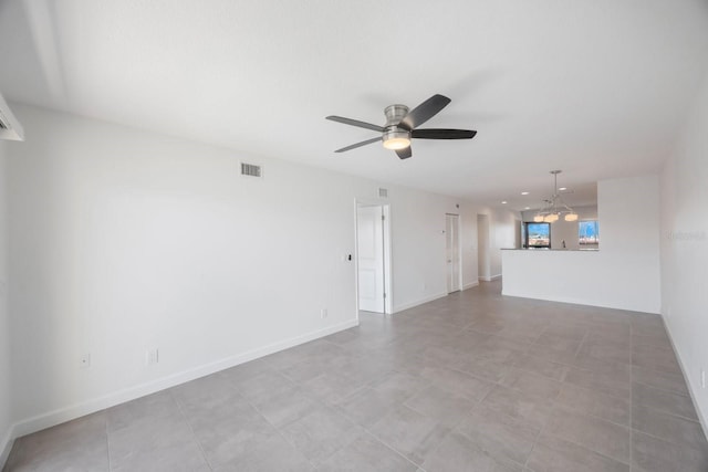 empty room with ceiling fan with notable chandelier and light tile patterned floors