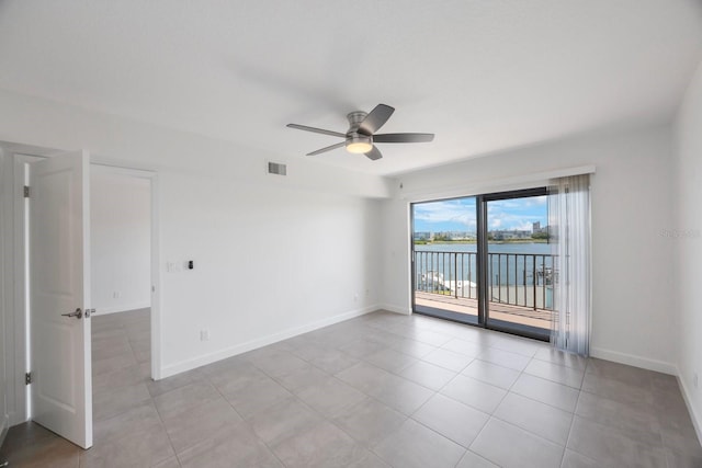 spare room featuring ceiling fan, light tile patterned flooring, and a water view