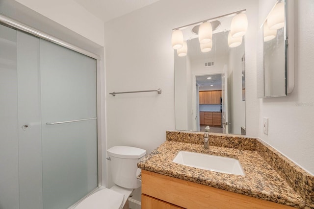 bathroom with vanity, a shower with shower door, and toilet