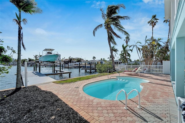 view of swimming pool with a boat dock, a water view, and a patio area