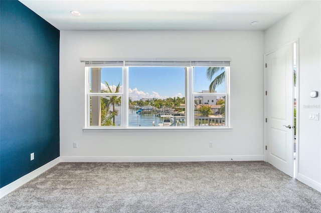 unfurnished room featuring carpet flooring and a water view