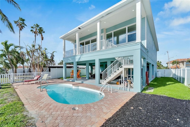 rear view of property featuring a fenced in pool and a patio area