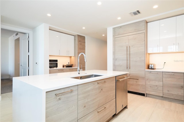 kitchen featuring a center island with sink, light tile patterned flooring, white cabinets, and sink