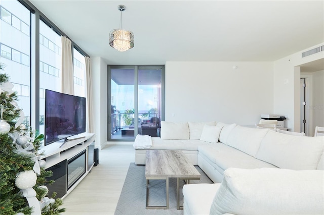 living room with expansive windows, light hardwood / wood-style floors, and an inviting chandelier