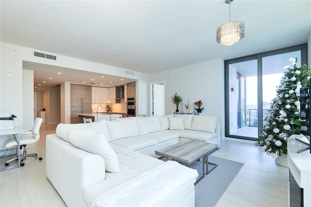 living room with an inviting chandelier, expansive windows, and sink