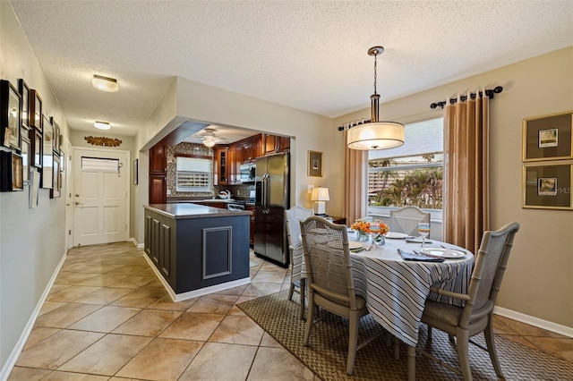 dining area featuring ceiling fan, light tile patterned flooring, and a textured ceiling