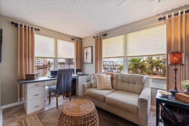 tiled home office with ceiling fan, plenty of natural light, and a textured ceiling