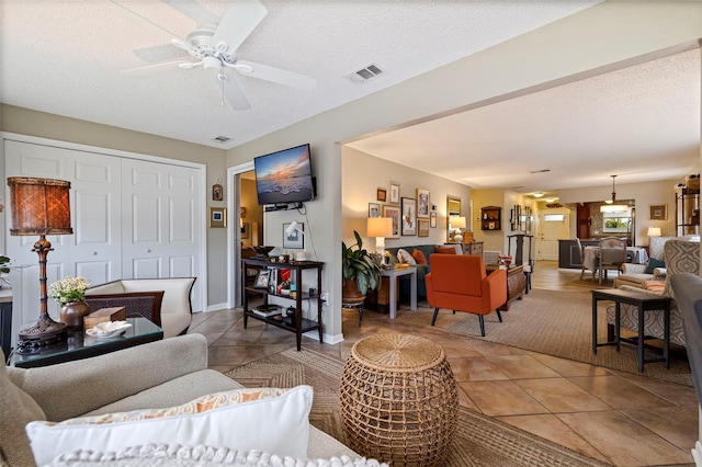 tiled living room featuring ceiling fan and a textured ceiling