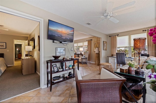 living room with ceiling fan, a textured ceiling, and light carpet