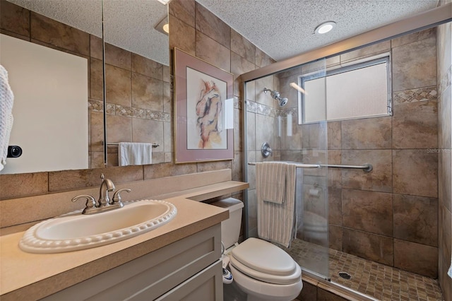 bathroom with a textured ceiling, toilet, a shower with door, and vanity