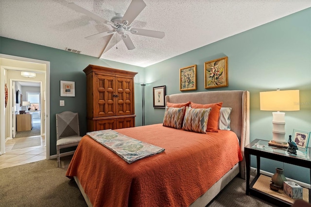 carpeted bedroom featuring ceiling fan and a textured ceiling