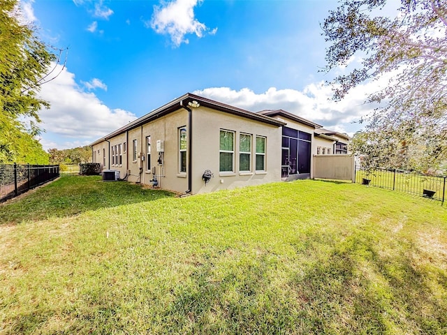 rear view of house featuring central AC unit and a lawn