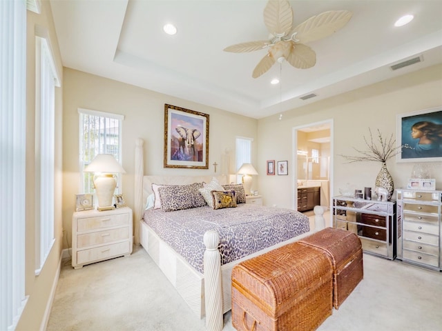 carpeted bedroom featuring connected bathroom, a raised ceiling, and ceiling fan