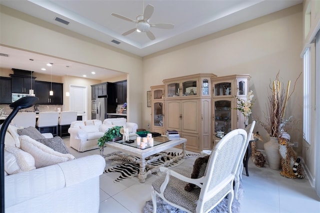 living room featuring light tile patterned floors, a raised ceiling, and ceiling fan