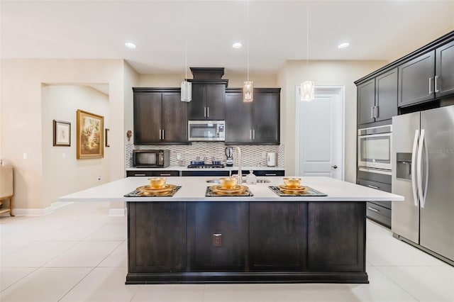 kitchen featuring an island with sink, pendant lighting, decorative backsplash, light tile patterned floors, and appliances with stainless steel finishes