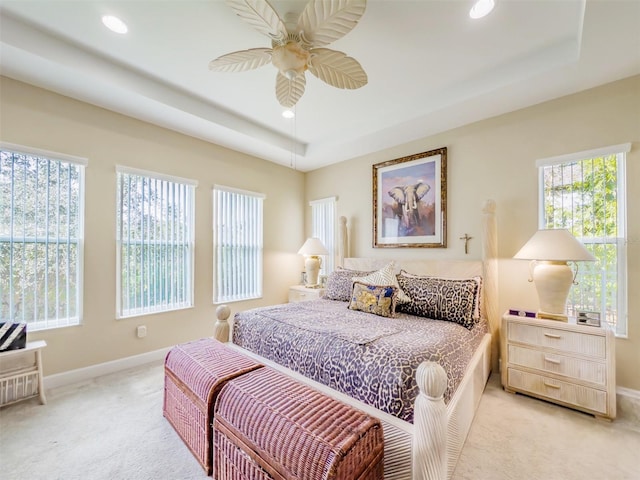 bedroom with a tray ceiling, ceiling fan, and light carpet