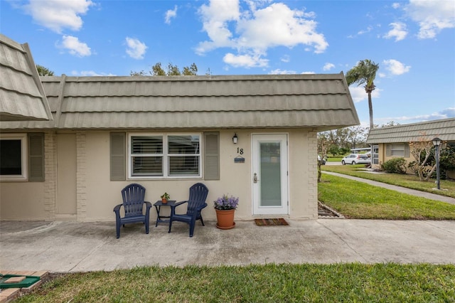 view of exterior entry featuring a patio area and a yard