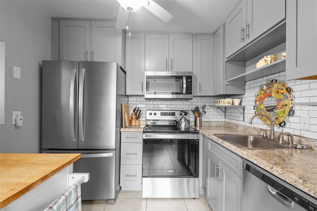 kitchen featuring ceiling fan, sink, backsplash, light tile patterned floors, and appliances with stainless steel finishes