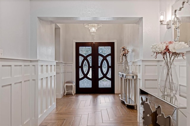 entrance foyer with dark parquet flooring, an inviting chandelier, and french doors