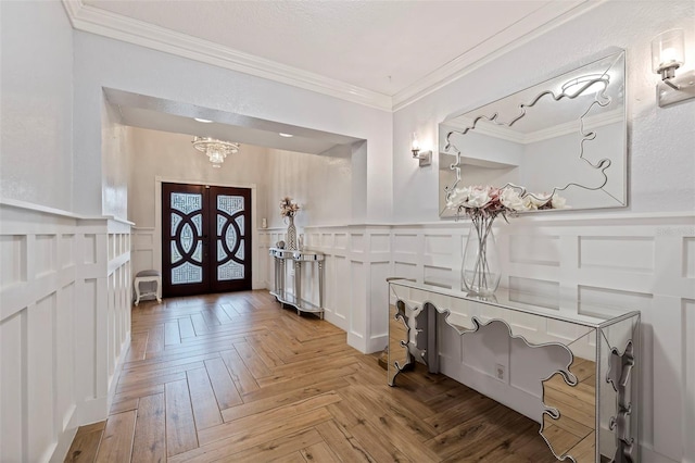 entrance foyer with crown molding, french doors, and light parquet floors