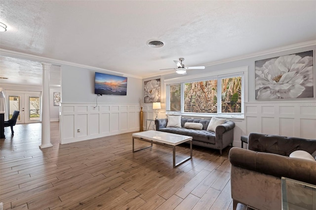 living room featuring decorative columns, ornamental molding, hardwood / wood-style flooring, and ceiling fan