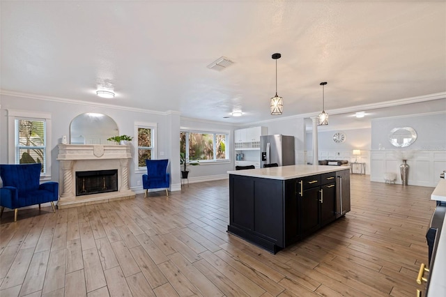 kitchen with crown molding, light hardwood / wood-style flooring, hanging light fixtures, a center island, and stainless steel fridge with ice dispenser