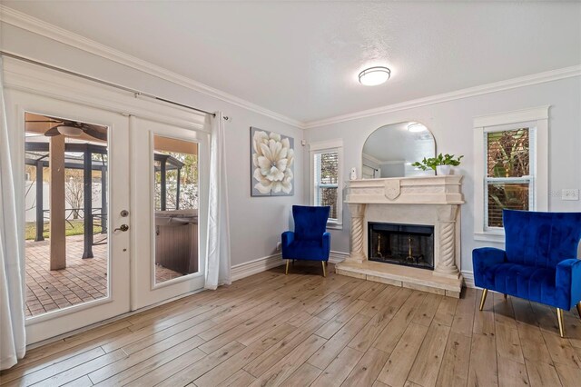 unfurnished room with french doors, ornamental molding, a fireplace, and light hardwood / wood-style flooring