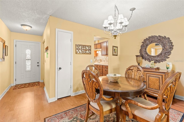 dining area featuring a notable chandelier, light hardwood / wood-style floors, and a textured ceiling