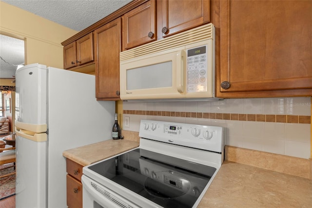 kitchen with a textured ceiling, white appliances, and tasteful backsplash