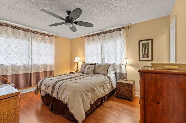 bedroom with ceiling fan, a textured ceiling, and light hardwood / wood-style flooring