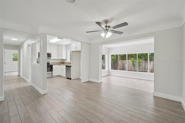 unfurnished living room with light wood-type flooring and ceiling fan